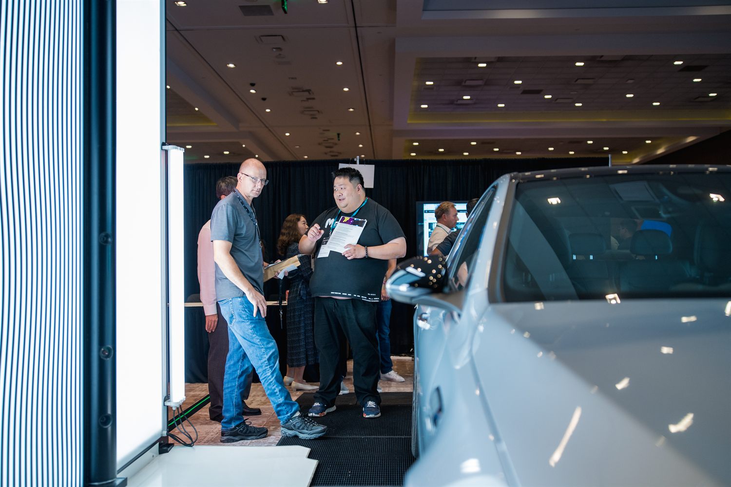 Attendees examining the scanning gate and reviewing printed information beside the vehicle