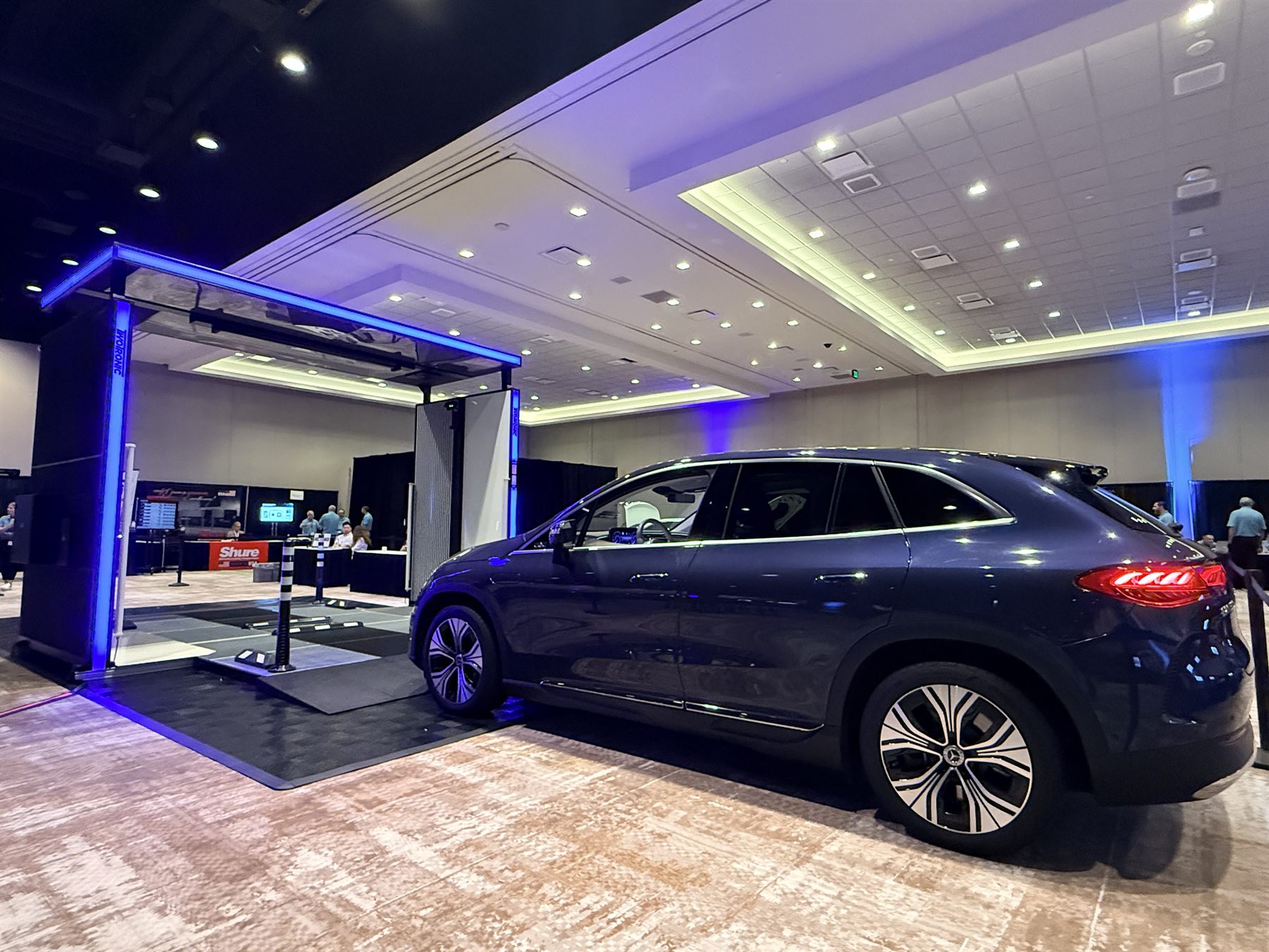 Scanning gate lit blue on the exhibition floor with an electric SUV alongside