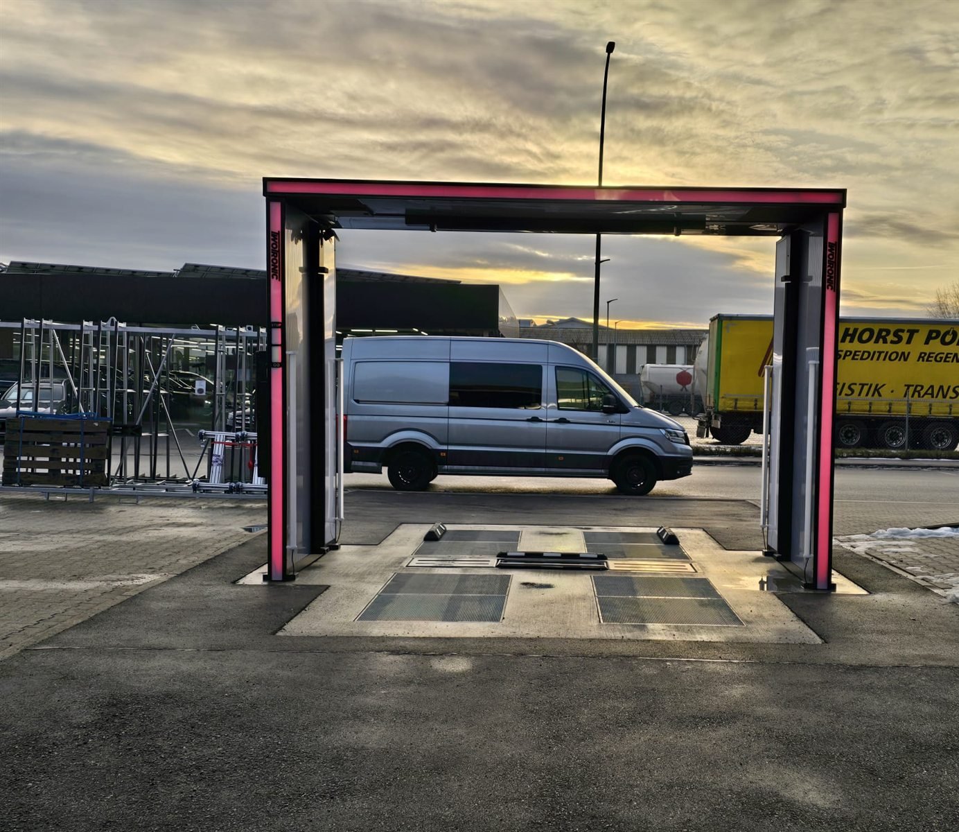 TwoTronic scanning gate with illuminated columns on a dealership forecourt at dusk